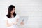 Beautiful of portrait young asian woman smiling and standing holding laptop on brick cement wall background