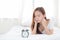 Beautiful of portrait young asian woman wake up in morning annoyed looking alarm clock.