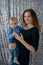 Beautiful portrait of a young mother and her son on a silver background of sequins