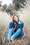 Beautiful positive girl in denim clothes sitting in autumn grass