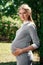 Beautiful pregnant girl in a park on a green background. Tenderness young woman enjoys nature outdoors. Pregnancy, family,