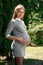 Beautiful pregnant girl in a park on a green background. Tenderness young woman enjoys nature outdoors. Pregnancy, family,