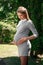 Beautiful pregnant girl in a park on a green background. Tenderness young woman enjoys nature outdoors. Pregnancy, family,