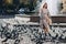 Beautiful pregnant mother stands near the pigeons in a sunny summer park. Walking on the street