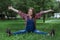 Beautiful pregnant woman in denim overalls sitting on the grass in the park