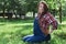 Beautiful pregnant woman in denim overalls sitting on the grass in the park