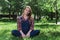 Beautiful pregnant woman in denim overalls sitting on the grass in the park