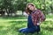 Beautiful pregnant woman in denim overalls sitting on the grass in the park