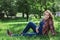 Beautiful pregnant woman in denim overalls sitting on the grass in the park