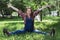 Beautiful pregnant woman in denim overalls sitting on the grass in the park