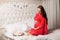 Beautiful pregnant woman dressed in elegant negligee sitting on the bed