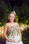 Beautiful pregnant woman in a floral dress sits in a Park outdoo