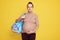 Beautiful pregnant woman with hair bun holds bag with baby`s things, prepares different items for newborn child going in maternit