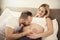 Beautiful pregnant woman and her handsome husband spending time together in bed kiss belly