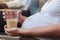 Beautiful pregnant woman holding a glass of milk and keeping a hand on her bare tummy while sitting