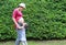 Beautiful pregnant woman with little girl kissing mother`s tummy in green garden