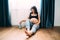 Beautiful pregnant woman smoothing her tummy and smiling, sitting in baby room