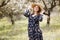 A beautiful pregnant woman in a straw hat in the spring flowering park. The expectant mother walks in the spring garden. Waiting