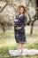 A beautiful pregnant woman in a straw hat in the spring flowering park. The expectant mother walks in the spring garden. Waiting