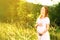 Beautiful pregnant woman in summer nature meadow in sunset