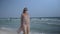 Beautiful pregnant woman walking on the ocean beach, Young woman waiting for her baby, stroking his stomach 4k
