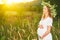 Beautiful pregnant woman in wreath relaxing in summer nature