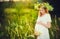 Beautiful pregnant woman in wreath relaxing in summer nature