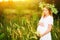 Beautiful pregnant woman in wreath relaxing in summer nature