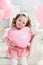 Beautiful preschool girl in a white studio with pink heart-shaped balloons