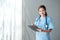 Beautiful and professional Asian female doctor in uniform with stethoscope open palm, smiling, looking at camera