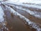 Beautiful puddles with ice crust, snow and reflection in winter or spring