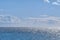 Beautiful puffy clouds in a blue sky rolling over a calm blue sea and ocean in summer. Gorgeous scenic view of the beach