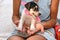 A beautiful puppy with a pink ribbon around his neck sits on the woman palms