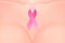 Beautiful realistic female breast with pink ribbon close-up.