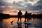 Beautiful rear view on couple of people on sup boards on the river at sunset