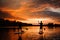 Beautiful rear view of two people on sup boards which floating on the river at sunset