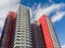 Beautiful red-black-white facades of new high-rise apartment buildings in the blue sky. Bottom view