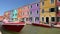 Beautiful red boat in the canal of Venice, colorful colorful houses on the island of Bruno