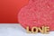 A beautiful red and gold candy box on a white table with a red background. Cork letters spell the word love