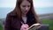 Beautiful red hair Caucasian female student is sitting in a park writing in her journal