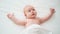 Beautiful red-haired baby lies on a white bed.