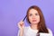 Beautiful red-haired girl with blue eyes in a white t-shirt thinks what to write in a notebook. Close-up, skin retouching