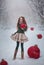 Beautiful red-haired girl like a doll with huge Christmas red balls walks in the winter fairy forest. Christmas card.