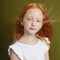 Beautiful red-haired girl with long hair and beautiful big blue eyes. Redhead Girl child in summer clothes posing on the