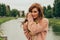 beautiful red-haired girl.picture against the background of the river, water, lake in the park, summer.sadness, expectation