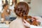 Beautiful red-haired hairy girl, hairdresser weaves a French braid, close-up in a beauty salon.