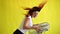 A beautiful red-haired woman is cooled off standing over a large electric fan on a yellow background