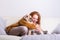 Beautiful red-haired woman embraces her dog on the couch
