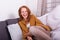 Beautiful, red-haired woman with orange sweater sits laughing on