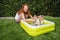 Beautiful red-haired woman plays with her dog in the garden